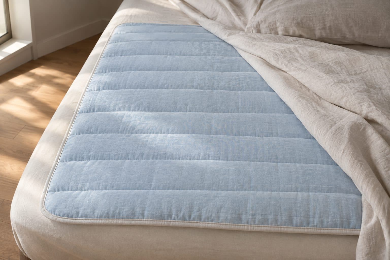 De ijsblauwe mat op een matras, het hoeslaken teruggeslagen